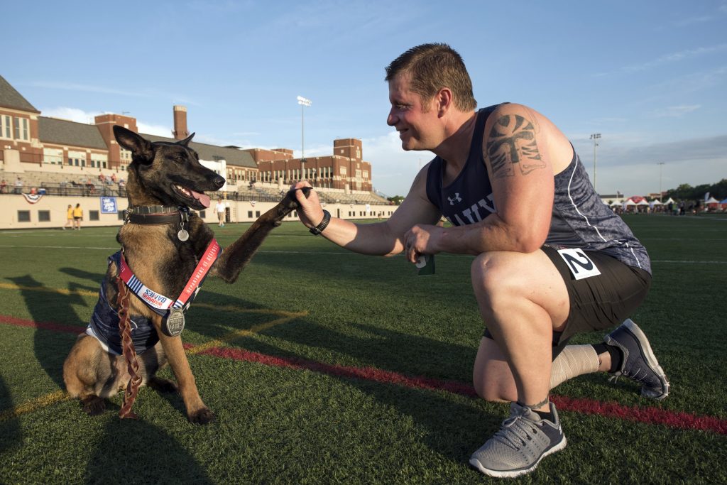 Navy veteran CPO Ron Condrey gets a high five from his service dog Via after Condrey medaled in track during the 2017 Department of Defense (DoD) Warrior Games at Lane Tech in Chicago, Ill., July 2, 2017. The DoD Warrior Games are an annual event allowing wounded, ill and injured service members and veterans to compete in Paralympic-style sports including archery, cycling, field, shooting, sitting volleyball, swimming, track and wheelchair basketball.    (DoD photo by Roger L. Wollenberg)