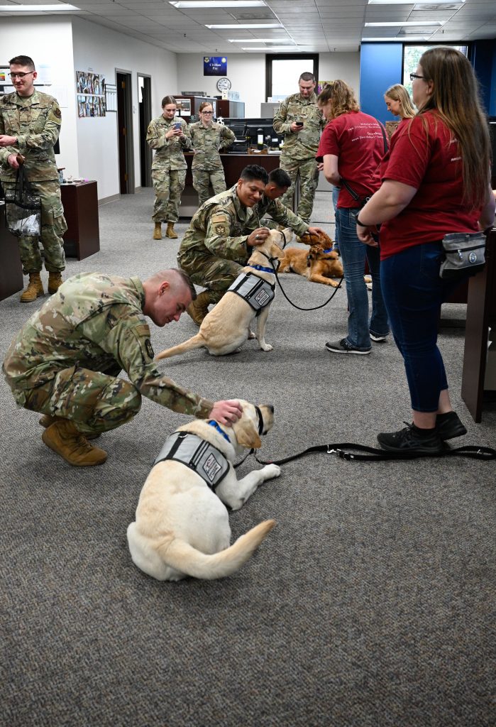 Airmen with the 509th Comptroller Squadron interact with Retrieving Freedom service dogs in-training, as part of the Post-Traumatic Stress Disorder awareness month at Whiteman Air Force Base, Missouri, June 28, 2022. PTSD is a mental health disorder that may develop after experiencing or witnessing a traumatic event. (U.S Air Force Photo by Senior Airman Christina Carter)