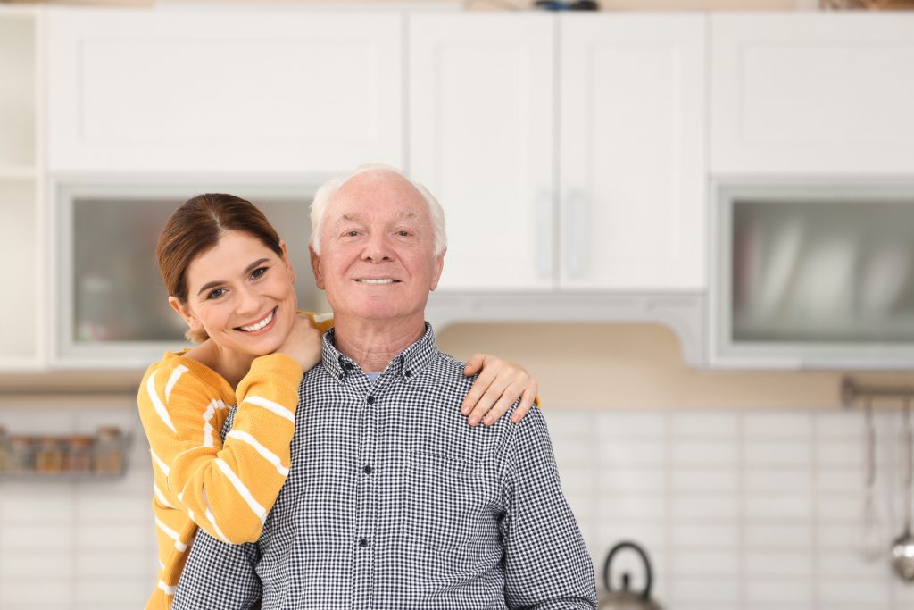 Elderly man with female caregiver in kitchen. Space for text